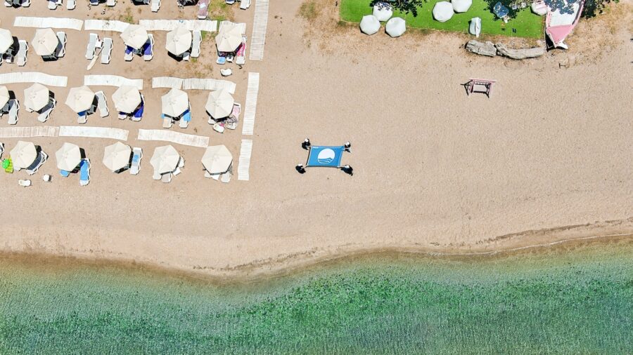 Aerial view of a beach with umbrellas and a trampoline / Description automatically generated