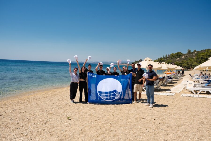 A group of people holding a flag on a beach / Description automatically generated